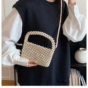 Vista dettagliata di una elegante borsa a tracolla in perline di legno indossata dal modello.