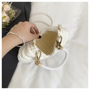 White woven shell handbag detail view, elegant pearl chain and golden hardware design.