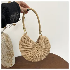 Detailed view of the khaki seashell shaped crochet handbag with braided handle and gold hardware.