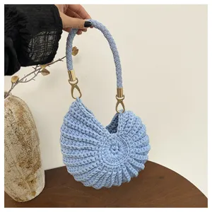Closeup of light blue handmade crochet shell handbag with metallic golden hardware details.