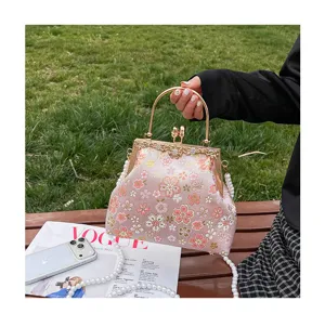 Gedetailleerd overzicht van de roze geborduurde handtas met bloemen en parelriem.
