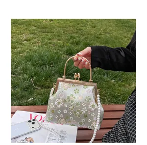 Gedetailleerd overzicht van vintage geborduurde bloemen tas met ketsluiting en parelband.