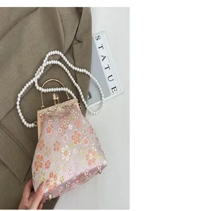 Detail van de geborduurde bloemen schelp handtas met parelriem elegante avondtas.