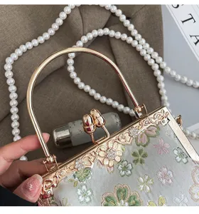 Elegante geborduurde avondtas met bloemen, gouden metalen frame en parelkettingriem.