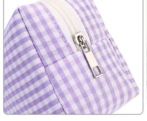 Nahaufnahme des lila Karomusters der Kosmetiktasche mit feiner Stofftextur und Reißverschluss.