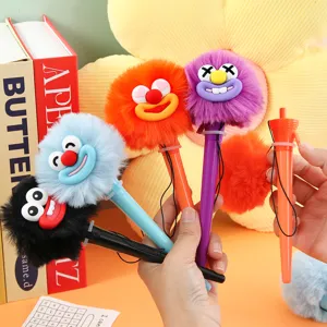Close-up detail showing colorful fluffy monster plush gel pens held in hand, cute stationery.