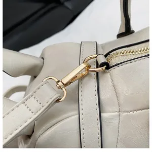 Detailaufnahme einer beigen unregelmässigen Tierschultertasche mit goldenen Beschlägen.