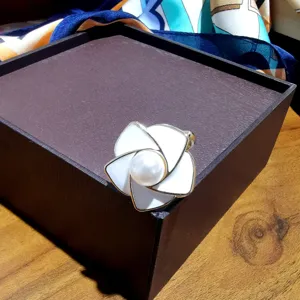 Détail élégant de boucle d'écharpe fleur de camélia avec émail blanc et perle.