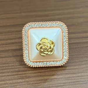 Vista dettagliata della fibbia per sciarpa quadrata con strass di camelia, cristalli e tono oro.