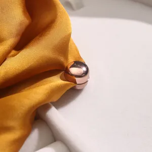 Detail shot of rose gold round hijab magnet pin holding golden silk scarf, no snag design.