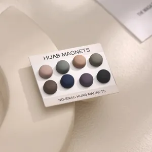 Matte round hijab magnets set in neutral packaging, close-up view of multicolored magnetic pins.
