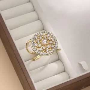 Primo piano di una lussuosa fibbia per sciarpa dorata con strass e perla in scatola bianca.