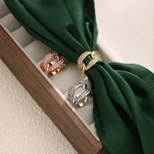 Vue détaillée d'anneaux de foulard en strass dorés, argentés et rosés sur ruban de soie.