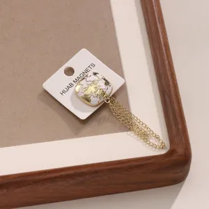 Detail shot of a square magnetic buckle with delicate chain and ginkgo leaf pattern.