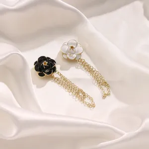 Detail view of black and white camellia magnetic hem clip with delicate golden chain accessory