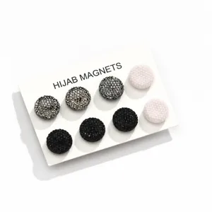Primo piano di magneti rotondi per hijab con glitter e colori solidi su cartella espositiva.