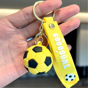 Close-up detail of yellow cartoon PVC soccer keychain pendant with GOOOOAL text.