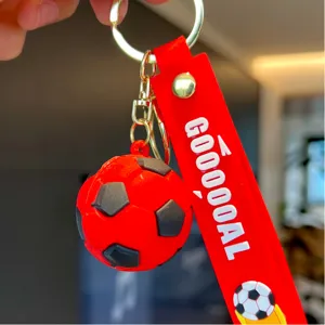 Close-up detail shot of red silicone football keychain with metal ring and GOOOOAL strap.