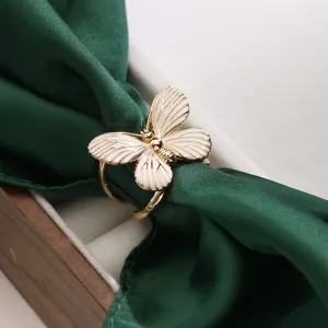 Vista dettagliata di una squisita fibbia per foulard in seta a farfalla dorata con smalto bianco.