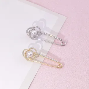 Primo piano dettagliato di spille di sicurezza con strass scintillanti e perla.