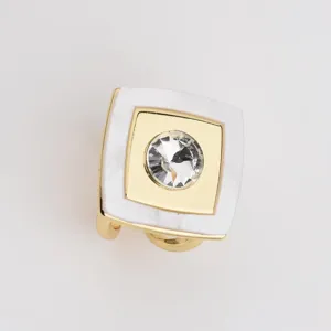 Detailed shot of a square scarf ring with gold metal frame white acrylic and central rhinestone.