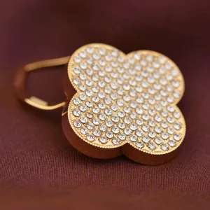 Gold-plated rhinestone four-leaf clover brooch detail, elegant sparkling scarf clip macro shot.