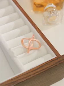 Close-up detail shot of the elegant rose gold X-shaped metal scarf buckle in a jewelry box.