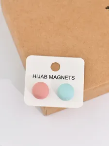 Round hijab magnet detail shot in pink and blue matte metal, secure anti-slip fastener.