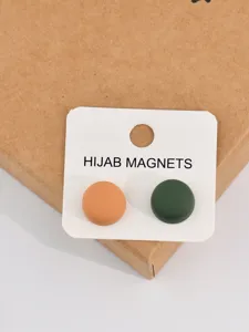 Close-up detail of two matte round hijab magnets in peach and green on display card.