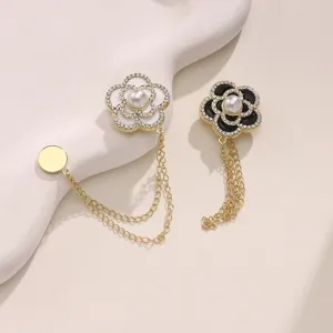 Detailopname van luxe camelia bloem broche met strass steentjes, parels en bungelende kettingen.
