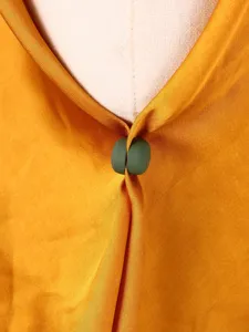 Dettaglio del bottone magnetico per vestiti, forte chiusura per sciarpe e hijab verde.