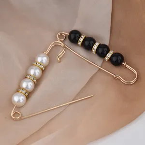 Dettaglio in primo piano di eleganti spille di sicurezza grandi dorate con perle e perline nere.