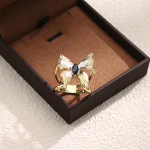 Detaillierte Nahaufnahme einer goldenen Schmetterlings-Schalschnalle mit weißem Email und Stein.