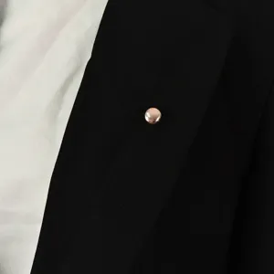 Gedetailleerd close-up van een roségouden magneetknoop op zwarte lap, elegante anti-glans speld.