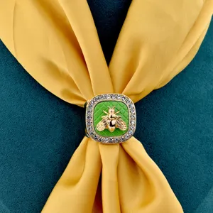 Gold square scarf ring featuring green quilted enamel and central bee detail with rhinestones.