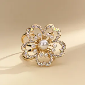 Close-up detail of the elegant gold metal flower silk scarf buckle with pearls and rhinestones.