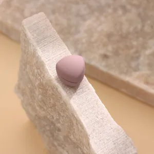 Close-up of a matte pink triangular magnetic scarf clip detail, smooth texture on stone.