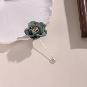 Primo piano dettaglio della spilla con rosa in tessuto grigio-verde, accessorio abbigliamento.
