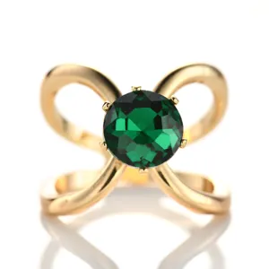 Elegant gold-tone scarf ring with a central green crystal and bow design, perfect for styling.