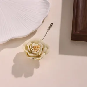 Spilla di rosa in tessuto beige, vista dettagliata di fiore artificiale per abbigliamento.