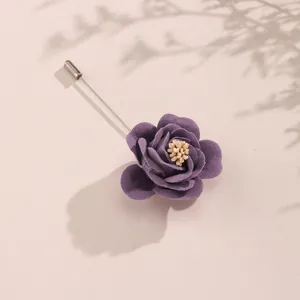 Primo piano dettagliato di una spilla a rosa in tessuto viola con petali fini e spilla.