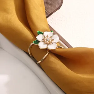 Close-up detail of golden enamel gardenia flower scarf ring buckle with sparkling rhinestones.