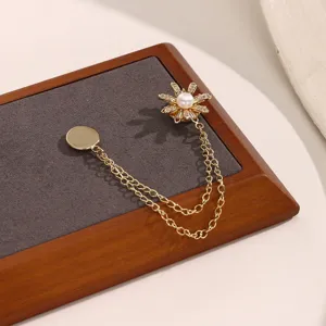 Gedetailleerde opname van de elegante gouden madeliefje magneetbroche met sprankelende steentjes en parel.