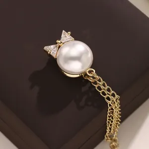 Gedetailleerd close-upgezicht van de gouden parel strik magnetische broche met glanzende kettingen.