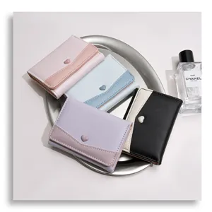 Detailopname van trendy pastel drievoudige portemonnee met schattige hart drukknoop.