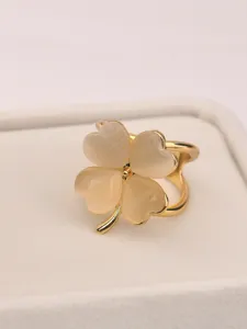 Detail shot of a golden four-leaf clover silk scarf buckle with cat's eye stone petals.