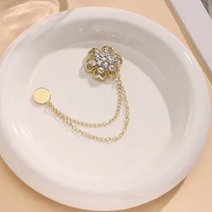 Gedetailleerd opname van een gouden strass bloem magnetische gesp met dubbele kettingen voor sjaals.