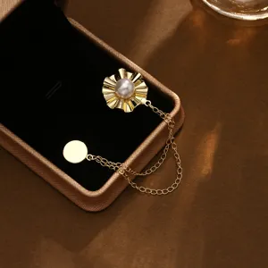 Detailopname van elegante gouden magnetische sjaalgesp met parel en dubbele ketting in sieradendoos.