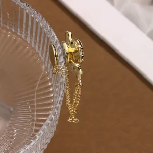 Close-up van gouden magnetische broche met dubbele kettingen op glas, kledingaccessoire.