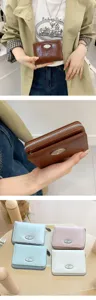 Detailed view of women's short wallet with zip closure and elegant metal clasp design.